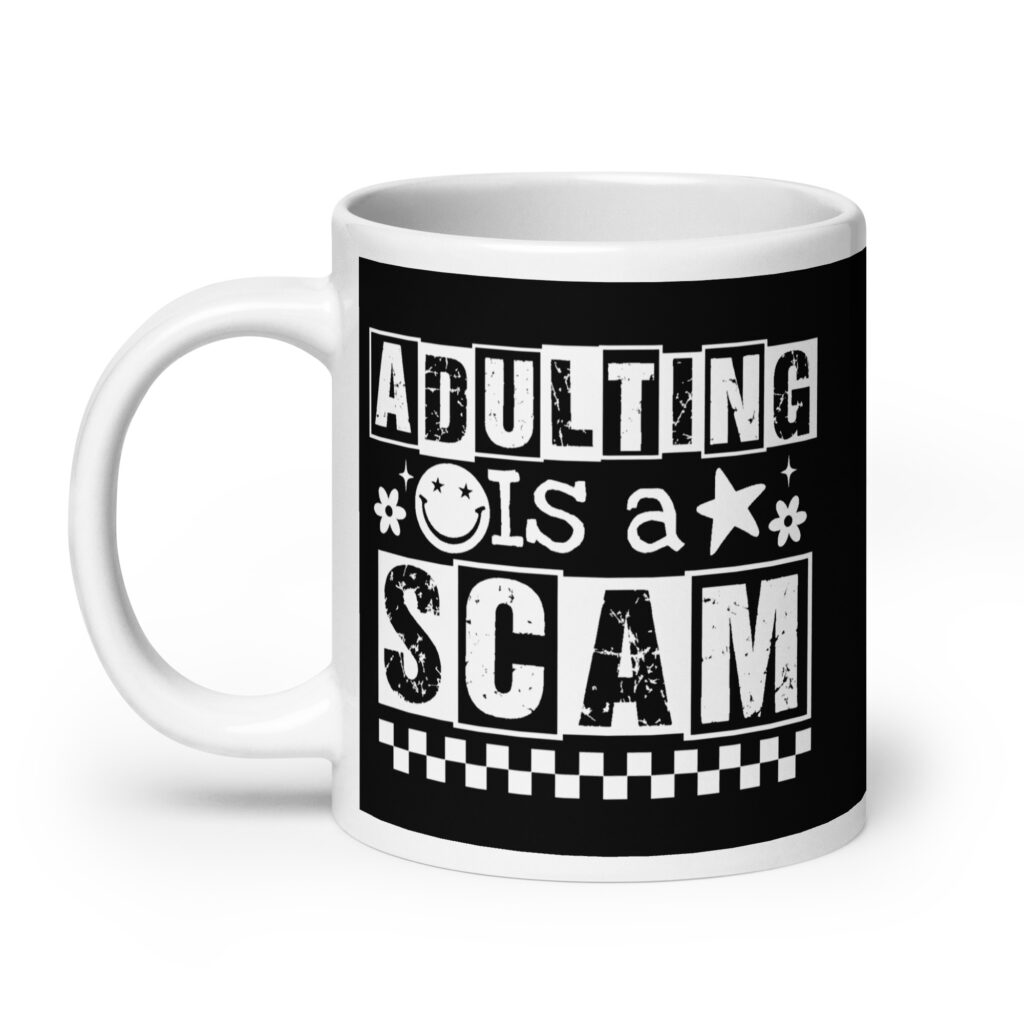 White ceramic mug featuring a black wraparound design with bold distressed white text reading ‘Adulting is a Scam.’ The text includes a smiley face, star, and flower icons, with a white checkerboard stripe along the bottom.