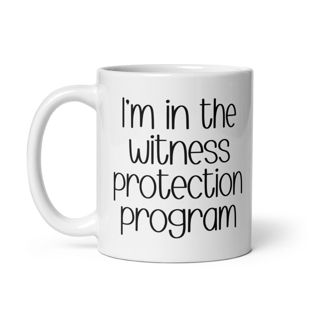 White ceramic mug with the text 'I'm in the witness protection program' printed on both sides.