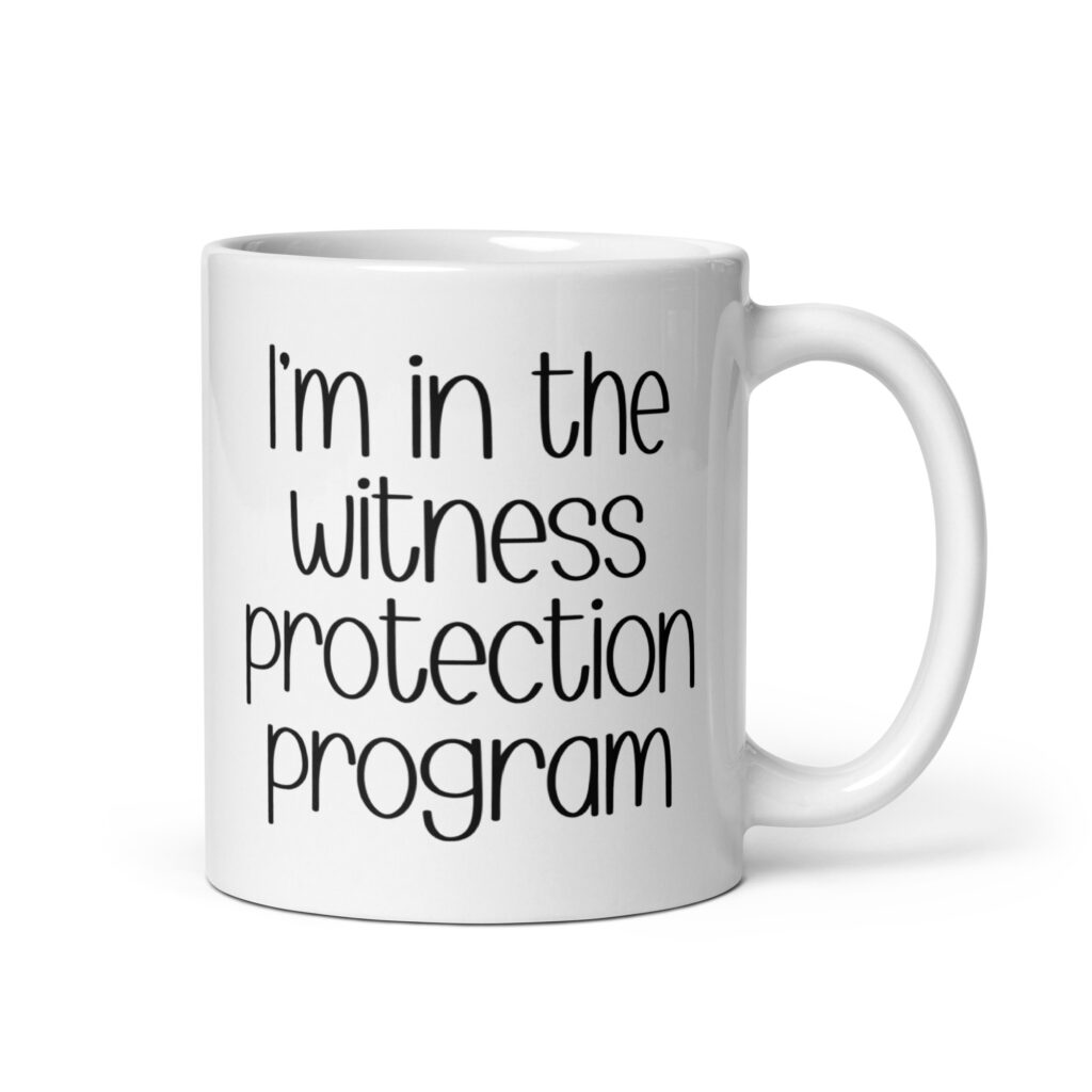 White ceramic mug with the text 'I'm in the witness protection program' printed on both sides.