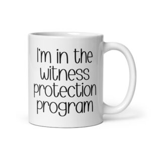 White ceramic mug with the text 'I'm in the witness protection program' printed on both sides.