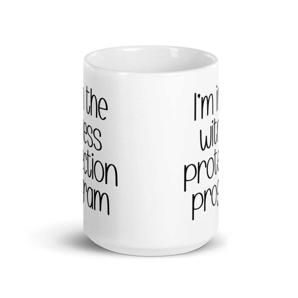 White ceramic mug with the text 'I'm in the witness protection program' printed on both sides.