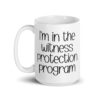 White ceramic mug with the text 'I'm in the witness protection program' printed on both sides.