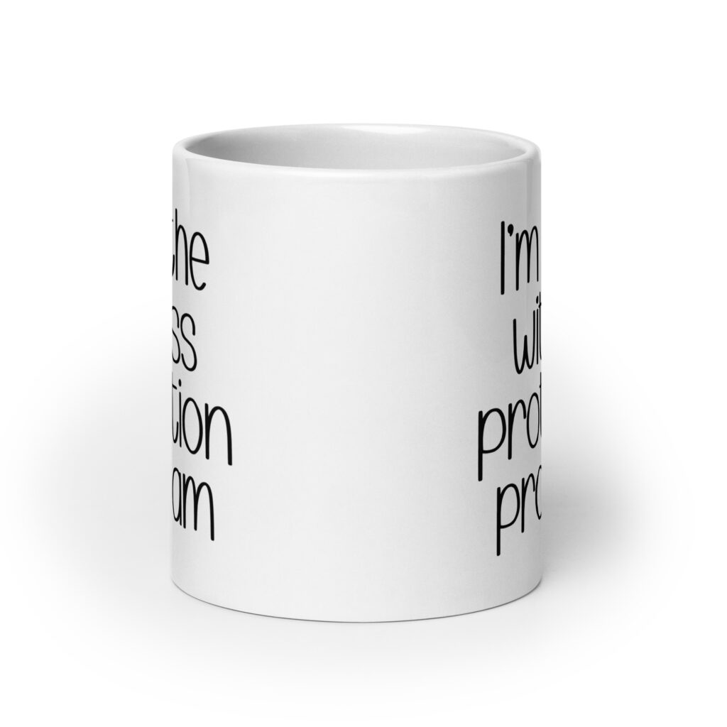 White ceramic mug with the text 'I'm in the witness protection program' printed on both sides.