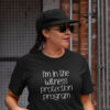 Woman wearing a black t-shirt with the text 'I'm in the witness protection program' printed on the front.